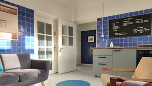 Een moderne woonkamer met een grijze bank, een blauwe ronde tafel en een kamerkleed met een patroon.