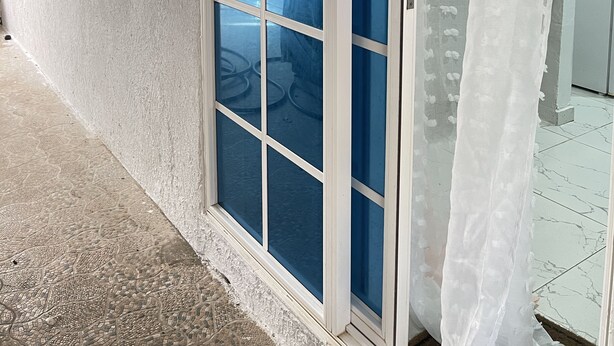 A room with a large sliding glass door, a white exterior wall, and a tiled floor. - Welcome to real paradise (San Luis)