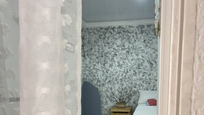 A bedroom with a bed, a small wooden side table, a potted plant, and a marble-patterned floor. - Welcome to real paradise (San Luis)