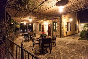 An outdoor patio area with stone flooring, wicker furniture, and hanging plants.