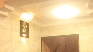 A modern lobby with a marble wall, a wooden staircase, and a grey sofa. - Sindz Palace Hotel (Yaoundé)