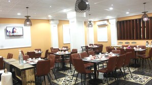 A conference room with multiple tables and chairs, a television screen, and decorative lighting. - Sindz Palace Hotel (Yaoundé)