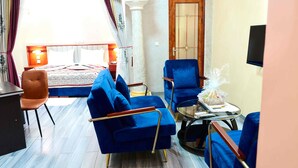 A hotel room with a bed, two blue armchairs, a small table, and a TV. - Sindz Palace Hotel (Yaoundé)