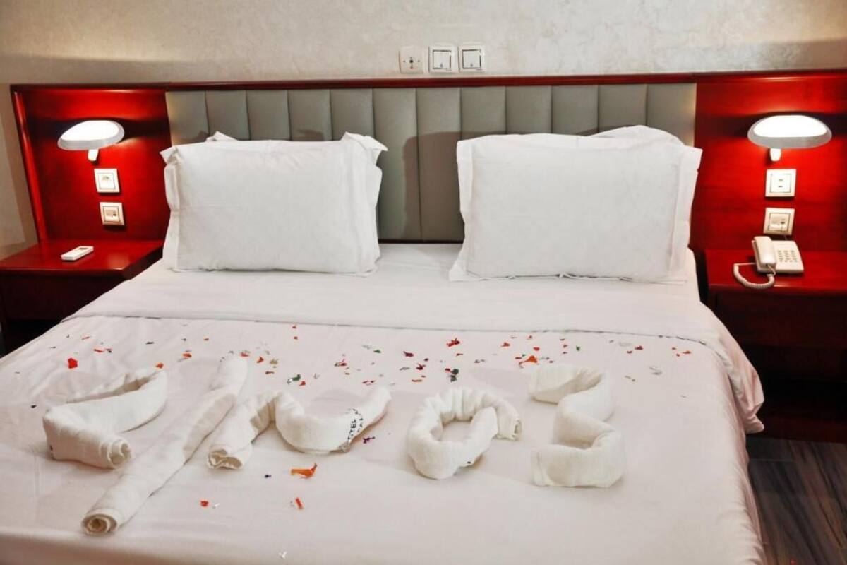 A hotel room with a neatly made bed, two bedside tables with lamps, and a headboard.