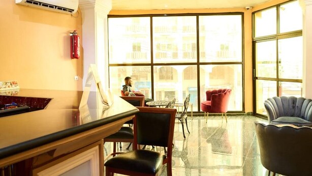 A hotel lobby with a reception desk, chairs, and large windows offering a view of the cityscape. - Sindz Palace Hotel (Yaoundé)