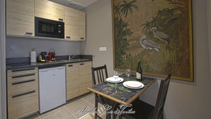 Una cocina compacta equipada con microondas, lavamanos y una mesa para dos personas, con platos y vasos.