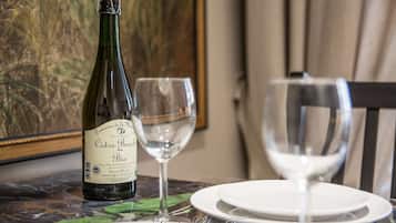Une bouteille de cidre bio « Domaine de la Minette Cidre Bouche » est posée sur une table, accompagnée de deux verres à vin et d’assiettes blanches.