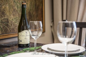 Une bouteille de cidre bio « Domaine de la Minette Cidre Bouche » est posée sur une table, accompagnée de deux verres à vin et d’assiettes blanches.