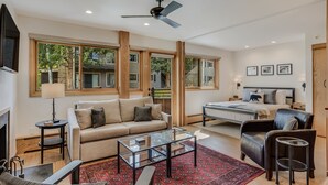 Un salon spacieux avec un canapé, une table basse et un tapis rouge à motifs.