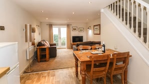 A dining area with a wooden table and chairs, a sofa, and a television. - The Mistal (Keighley)
