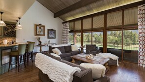 A spacious living area with a large window, a cozy seating arrangement, and a kitchen area with a bar. - Majestic Mountain Retreat | AC, Pool, Hot Tub, Golf & Ski (Durango)