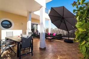 An outdoor patio with a dining table, chairs, a large umbrella, and a sofa with cushions. - 3 Bed/2 bath apt, terraces, pool, walk to beach (Lagos)