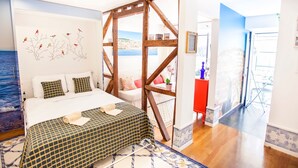 Una camera da letto con un letto, una struttura in legno a cavalletto, vista sul mare e un armadio rosso.