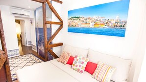 Una camera da letto con un letto, cuscini colorati, una sedia di legno, un quadro che raffigura una veduta cittadina e un tappeto decorato.