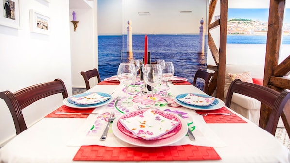 A dining table set for six with a view of the sea.