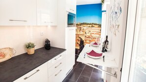Una cucina moderna con mobili bianchi, un piano di lavoro nero e vista sulla città attraverso una finestra.