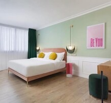 Un dormitorio moderno con cama, lámparas de noche, una pared verde y un cartel motivacional.