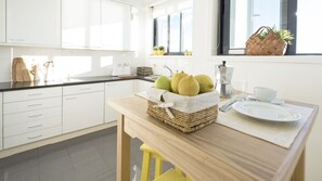 Une cuisine moderne avec des meubles blancs, un plan de travail en bois et un panier de fruits.