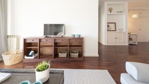 A living room with a wooden cabinet, a television, wicker baskets, and a white sofa.