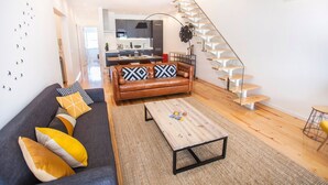 Una sala de estar moderna con un sofá de cuero, una mesa de centro de madera y una escalera.