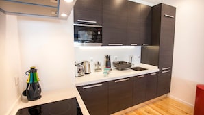 Una cocina moderna con armarios oscuros, un microondas Bosch, un lavamanos y una estufa.
