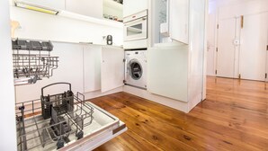 Une cuisine compacte équipée d’un lave-vaisselle, d’une machine à laver et d’un four encastré.