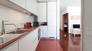 A modern kitchen with white cabinets, a stainless steel sink, and a red toaster.