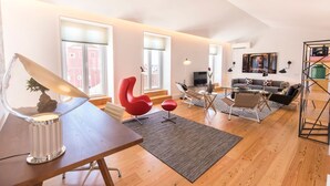 Un salon moderne avec un plancher en bois, une table à manger, des chaises rouges, un canapé et un téléviseur.