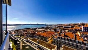 Paisagem costeira com uma ponte imponente, edifícios coloridos e vista para o mar.