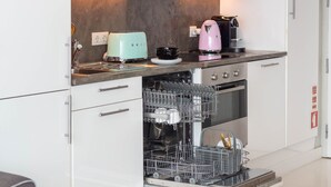 Uma cozinha com máquina de lavar louça, torradeira e cafeteira na bancada.