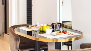 Mesa de jantar com tampo de vidro, rodeada por cadeiras estofadas marrons.