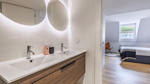 A modern bathroom with dual sinks, a wooden vanity, and a large mirror. - Penthouse on the Tagus in Alfama by LovelyStay (Lisboa)