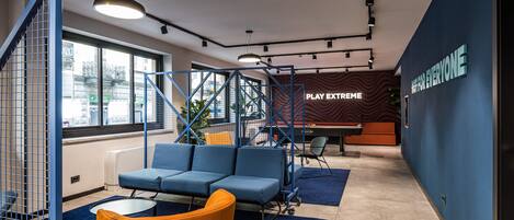A modern interior with a blue sofa, orange chair, and a 'PLAY EXTREME' sign on the wall.