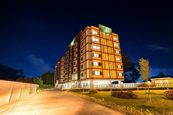 A multi-story hotel with a modern design, featuring a prominent green sign on the top. - OYO 338 V-twin Donjan Service Apartment (Chiang Mai)