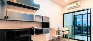 A modern hotel room with a balcony, a flat-screen TV, a desk with a chair, and a glass partition wall. - OYO 338 V-twin Donjan Service Apartment (Chiang Mai)