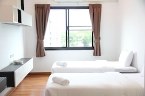 Une chambre d’hôtel avec deux lits, un bureau avec un téléphone et une fenêtre avec des rideaux.