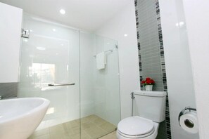 A modern bathroom with a glass shower enclosure, a white bathtub, and a toilet. - OYO 338 V-twin Donjan Service Apartment (Chiang Mai)