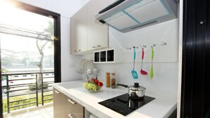 A modern kitchen with a black induction cooktop, white cabinets, and a window overlooking a green area.