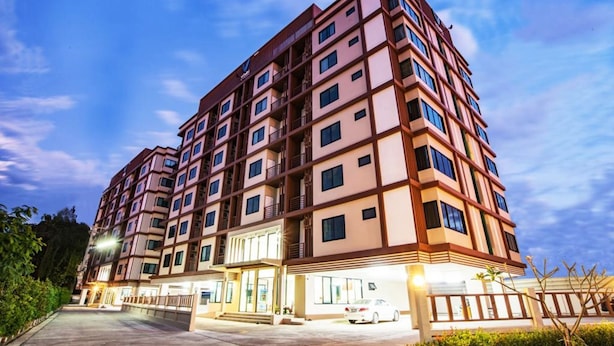A multi-story hotel with a modern design, featuring a prominent entrance and a parking area.