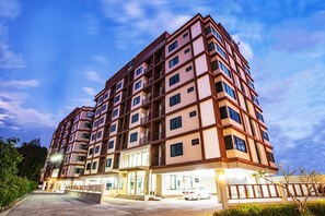 Um hotel com vários andares e design moderno, com uma entrada destacada e área de estacionamento.