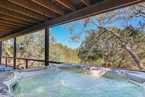 A hot tub with a view of trees and a wooden ceiling.