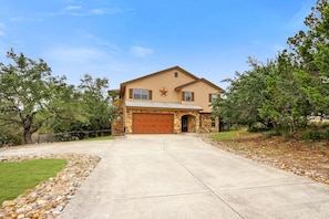 A two-story house with a garage, stone facade, and a star emblem on the front.