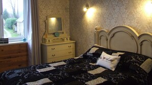 Ein Schlafzimmer mit Bett, Schminktisch und einem Fenster mit Vorhängen.