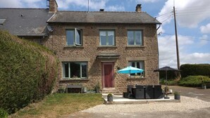 Ein Steinhaus mit einer Veranda, einer roten Tür und einem Schotterweg.