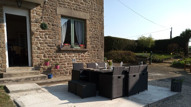 Ein Steinhäuschen mit einer Terrasse, die Gartenmöbel und Blumentöpfe umfasst.