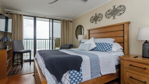 Une chambre d’hôtel équipée d’un lit, d’un bureau, d’une chaise, d’un balcon avec vue et d’un ventilateur de plafond.