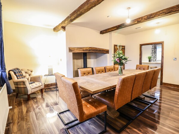 A dining area with a wooden table and leather chairs, a fireplace, and a large mirror on the wall. - Bodaioch Cottage (Caersws)