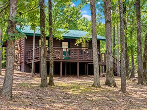 A cabin with a wooden deck, surrounded by trees. - Charming 1-Bedroom Log Cabin – Perfect for Family Getaways! (Broken Bow)