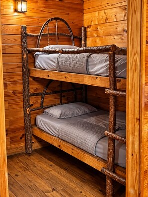 A bunk bed with a ladder, wooden walls, and a single light fixture. - Charming 1-Bedroom Log Cabin – Perfect for Family Getaways! (Broken Bow)