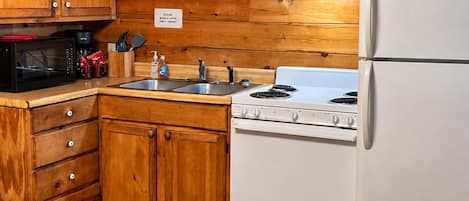 A kitchen with wooden cabinets, a microwave, a stove, and a refrigerator.
